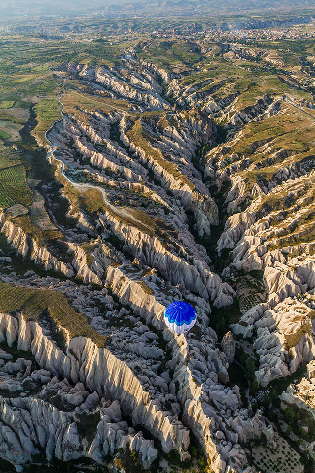 Sharp, jaggered landscape photograph of a Turkish valley and a hot air balloon 