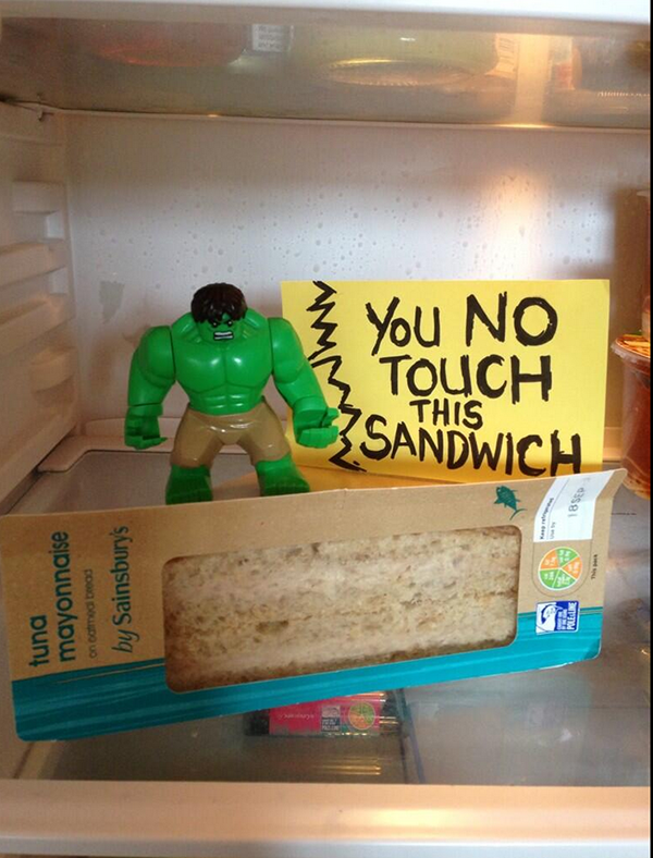 Funny written sticky note saying 'You No Touch This Sandwich' with a toy figurine Hulk seemingly guarding the sandwich.
