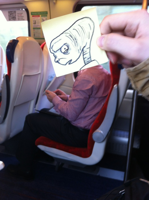 Funny drawing of ET looking a little angry and frustrated against a real life commuter sitting in the quiet zone on his phone on the train to work