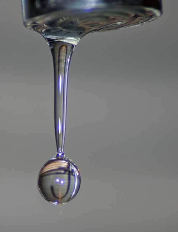 Up-close photo of a dripping tap just as the little blob is about to drop