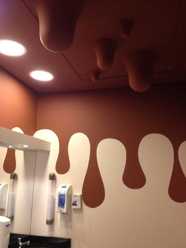 La photo du plafond des toilettes montre que le chocolat descend le long des murs et pend du plafond.